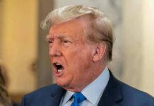 Man in suit with open mouth, speaking passionately.