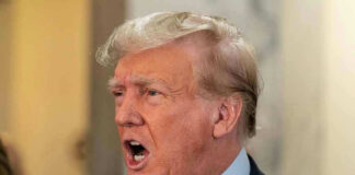 Man in suit with open mouth, speaking passionately.