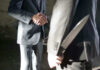 Two men shaking hands, one holding hidden knife.