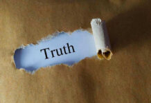 Ripped paper reveals word truth underneath brown surface