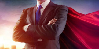 Businessman wearing a cape, standing confidently.