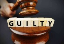 A gavel striking down next to wooden blocks spelling 'GUILTY'