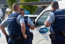 Three police officers discussing near a police vehicle
