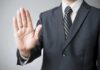 A man in a suit holding up his hand in a stop gesture