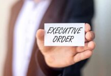 EMERGENCY Order Shakes Shutdown Fight Person holding a card that reads 'EXECUTIVE ORDER'