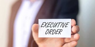 Person holding a card that reads 'EXECUTIVE ORDER'
