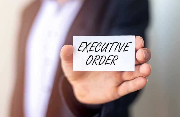 Person holding a card that reads 'EXECUTIVE ORDER'