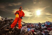 Person in protective gear standing on a landfill with a yellow container