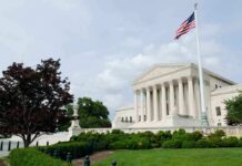 The U.S. Supreme Court building with an American flag and landscaped grounds