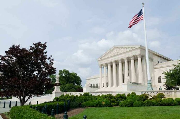 The U.S. Supreme Court building with an American flag and landscaped grounds