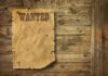A vintage wanted poster pinned to a wooden wall