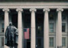 Economic Shockwave: Fed Chair Switch Stuns US Treasury Department building with statue and flag.