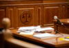 Wooden courtroom desk with papers and a microphone.