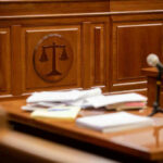 Wooden courtroom desk with papers and a microphone.