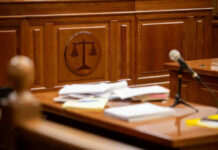 Wooden courtroom desk with papers and a microphone.