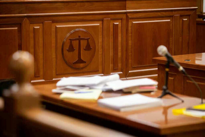 Wooden courtroom desk with papers and a microphone.