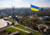 Large Ukraine flag with cityscape in background.