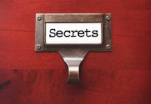 A label holder on a wooden surface with the word Secrets displayed