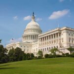 The U.S. Capitol building surrounded by green grass and trees under a blue sky