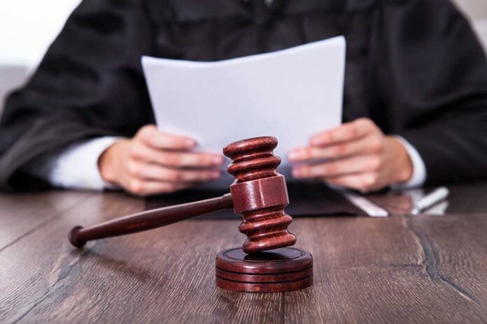 A judge holding documents with a gavel in the foreground