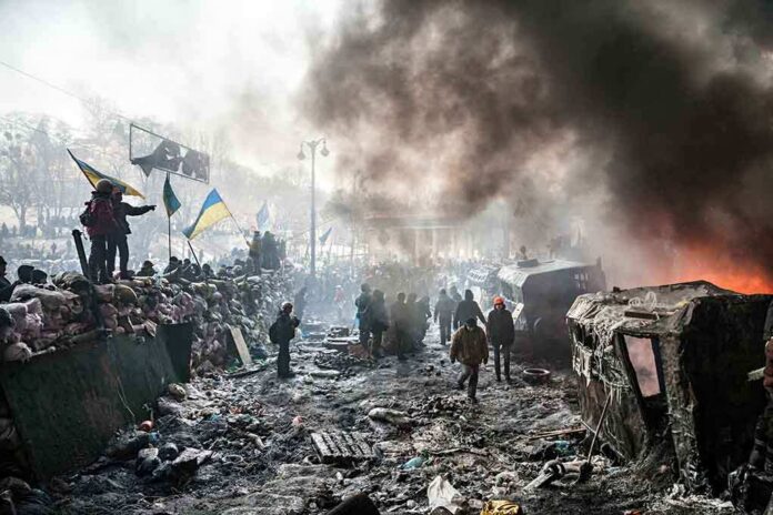 A chaotic protest scene with smoke, fire, and people holding flags