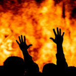 Holy Land Arson—Where’s The Outrage? Silhouetted hands raised against a fiery background.