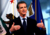 Money Trails Shadow California’s First Couple Man speaking with flags in the background