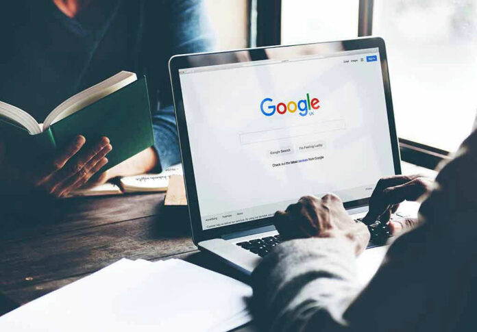 Laptop on Google homepage, person reading a book.