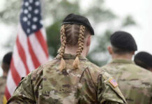 The Military Just Decided Which Faiths Count — 180 Didn’t Make It Soldier with braided hair in uniform, American flag visible.