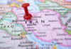 War, Cash, Silence — The Iran Draft Red pushpin marking Iran on a map.