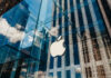 Apple store with glass facade and city reflections.