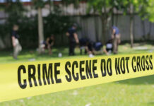 Yellow crime scene tape blocking grassy area.