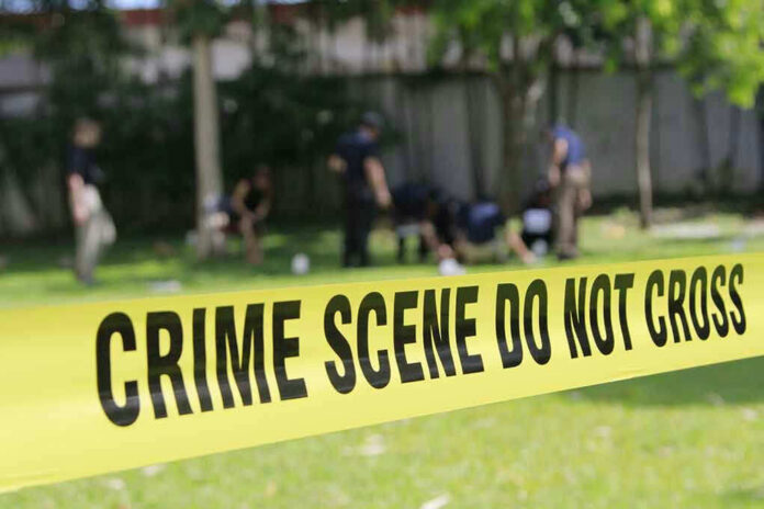 Yellow crime scene tape blocking grassy area.