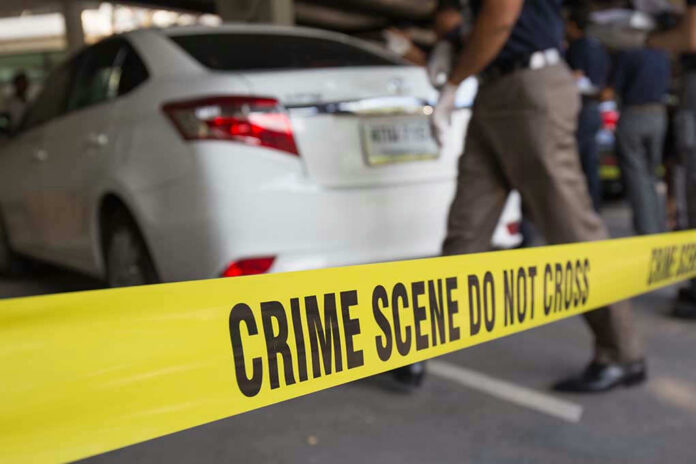 Crime scene tape blocking off white sedan.