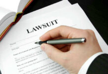 The $1.8B Anti-Weaponization Fund Is Dead — DOJ Told Courts in Writing Hand holding pen, filling out lawsuit form.