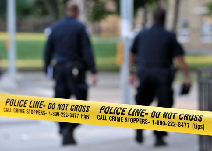 Toronto-july,17:,Police,Line,Do,Not,Cross,Tape,With,Two Police officers walking past caution tape at a crime scene