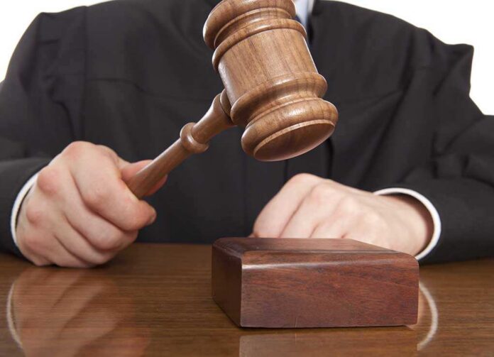 Judge.,Referee,Hammer,And,A,Man,In,Judicial,Robes A judge holding a gavel above a wooden block