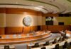 Court Clash Explodes: Title IX on Trial Interior view of a government chamber with wooden paneling and seating