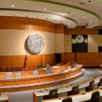 Court Clash Explodes: Title IX on Trial Interior view of a government chamber with wooden paneling and seating