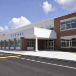Michigan Districts Under Fire Modern school building with large windows and a clear sky