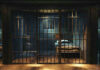 Empty prison cell with metal bars and bed.