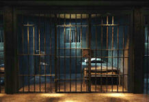 Overcrowded Hell Erupts — 25 Dead Empty prison cell with metal bars and bed.
