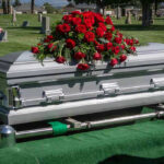 Silver casket with red roses in a cemetery.