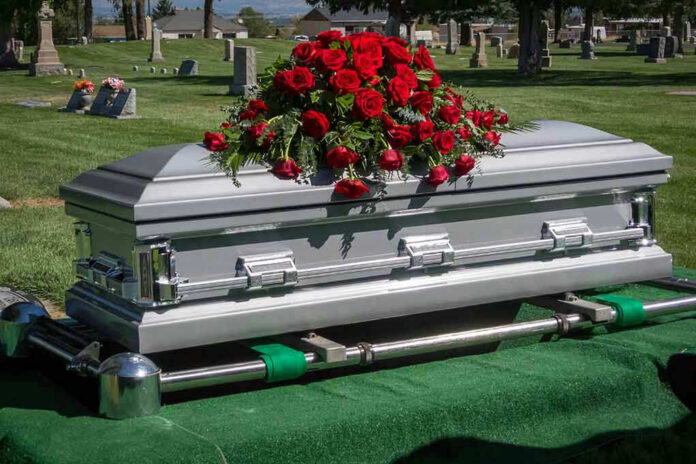 175194851 Silver casket with red roses in a cemetery.