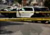 Illegal Dumping Unmasks Industrial Meth Hub Police tape blocking street with patrol cars.