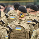 Soldiers in camouflage uniforms with Ukrainian flags.