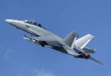 Twin-engine fighter jet climbing in a clear blue sky
