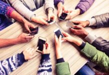 Hands around a table holding smartphones