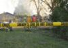 Smoking Blamed — Evidence Still Missing Yellow police tape marking a restricted area at a fire scene with firefighters in the background