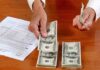 Billionaires Tax Bombshell—What’s Next? Hands counting cash and reviewing financial documents on a wooden table